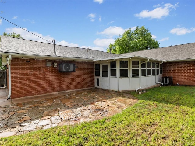 back of property with central AC, a patio, brick siding, a sunroom, and a yard