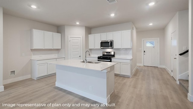 kitchen with appliances with stainless steel finishes, a sink, baseboards, light wood finished floors, and white cabinetry