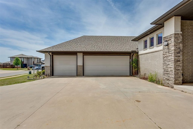 view of side of property featuring a garage, a shingled roof, driveway, and brick siding