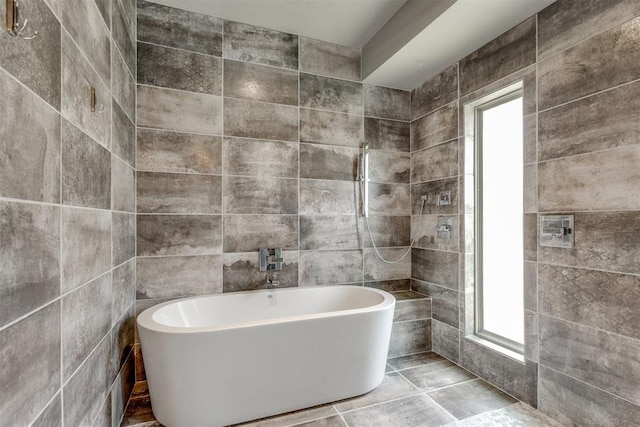 full bath featuring tile walls, a soaking tub, and tile patterned floors