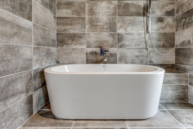 bathroom featuring tile walls and a soaking tub