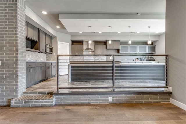 kitchen featuring baseboards, wall chimney range hood, recessed lighting, light wood-type flooring, and tasteful backsplash