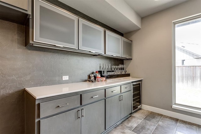 bar featuring backsplash, beverage cooler, and baseboards