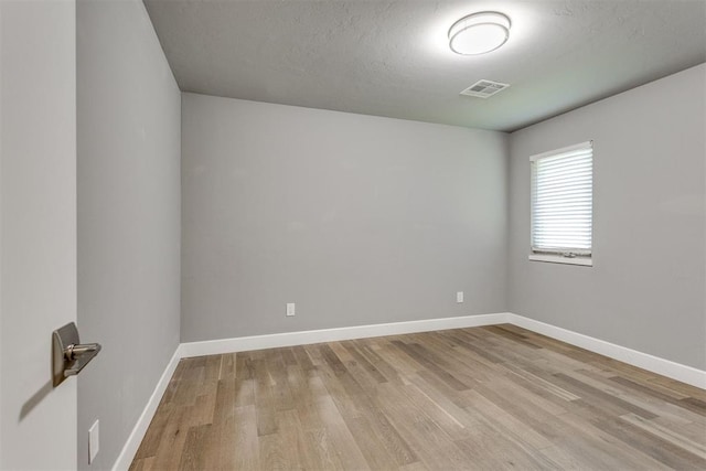 unfurnished room with baseboards, visible vents, and light wood-style floors