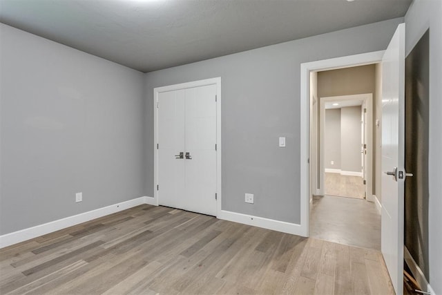 unfurnished bedroom with light wood-style floors, baseboards, and a closet