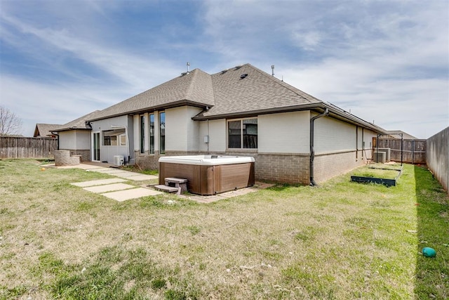 rear view of property with roof with shingles, a patio area, a hot tub, brick siding, and a fenced backyard