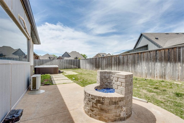 view of patio with a fenced backyard, a hot tub, central AC, and an outdoor fire pit