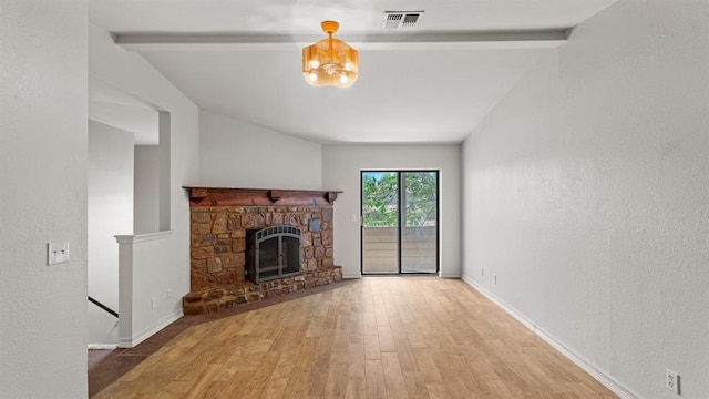 unfurnished living room with lofted ceiling with beams, a fireplace, baseboards, wood finished floors, and visible vents
