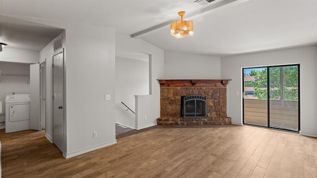 unfurnished living room featuring washer / dryer, a stone fireplace, wood finished floors, and visible vents