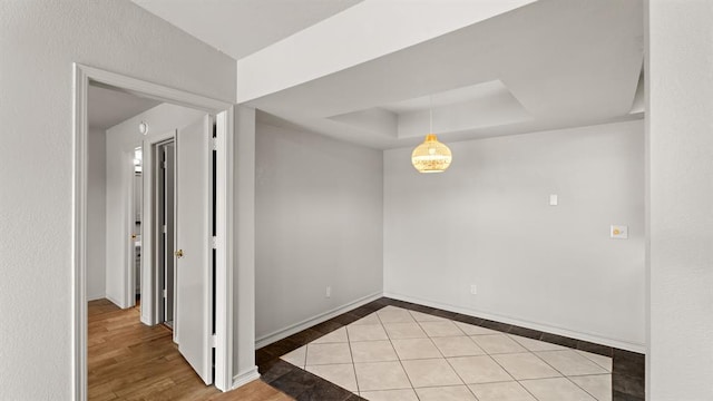 spare room with baseboards, tile patterned floors, and a raised ceiling