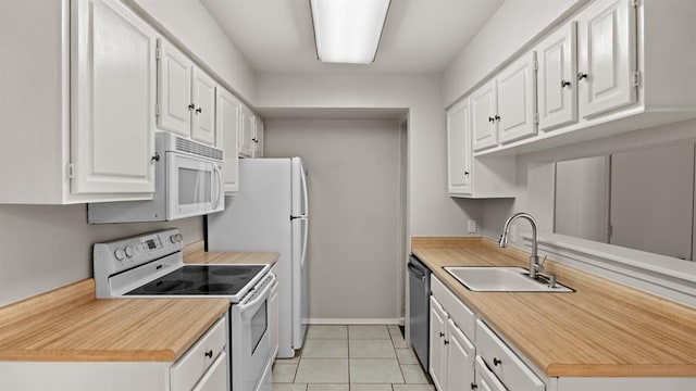 kitchen featuring a sink, light tile patterned floors, white cabinets, baseboards, and white appliances