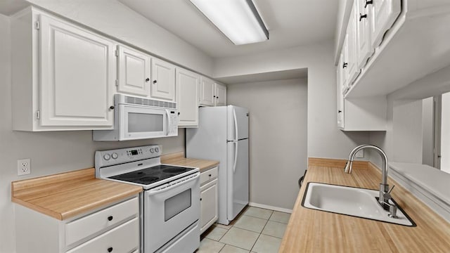 kitchen with white appliances, light countertops, white cabinets, a sink, and light tile patterned floors