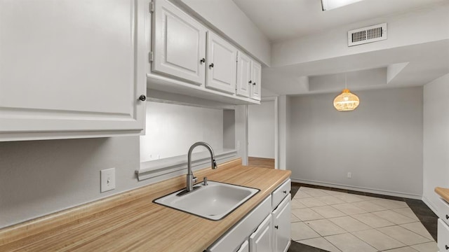 kitchen with white cabinetry, a tray ceiling, visible vents, and a sink