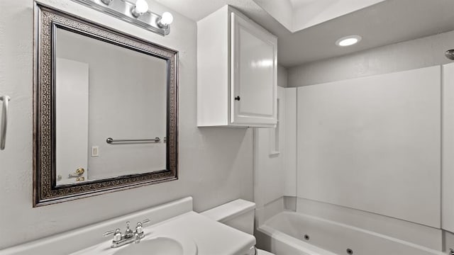 bathroom featuring shower / bathtub combination, toilet, and a sink