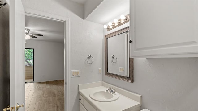 bathroom with a ceiling fan, a textured wall, wood finished floors, and vanity