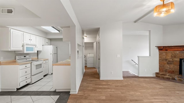 kitchen with visible vents, washer / dryer, white appliances, light countertops, and white cabinetry