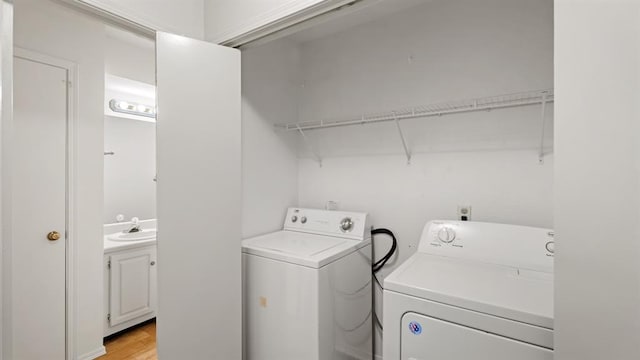 clothes washing area featuring a sink, washer and clothes dryer, light wood finished floors, and laundry area