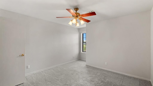 carpeted empty room with baseboards, ceiling fan, and visible vents