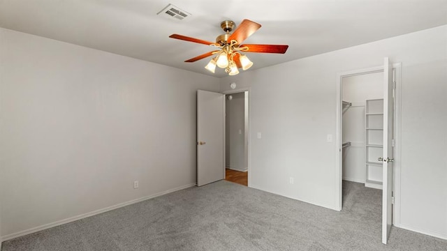 unfurnished bedroom with carpet flooring, a ceiling fan, a spacious closet, visible vents, and a closet