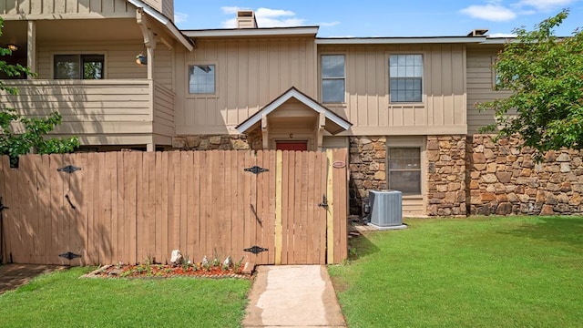 townhome / multi-family property with board and batten siding, a chimney, a gate, fence, and stone siding