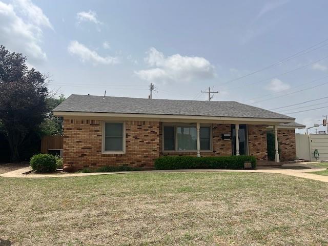 ranch-style home featuring brick siding and a front lawn