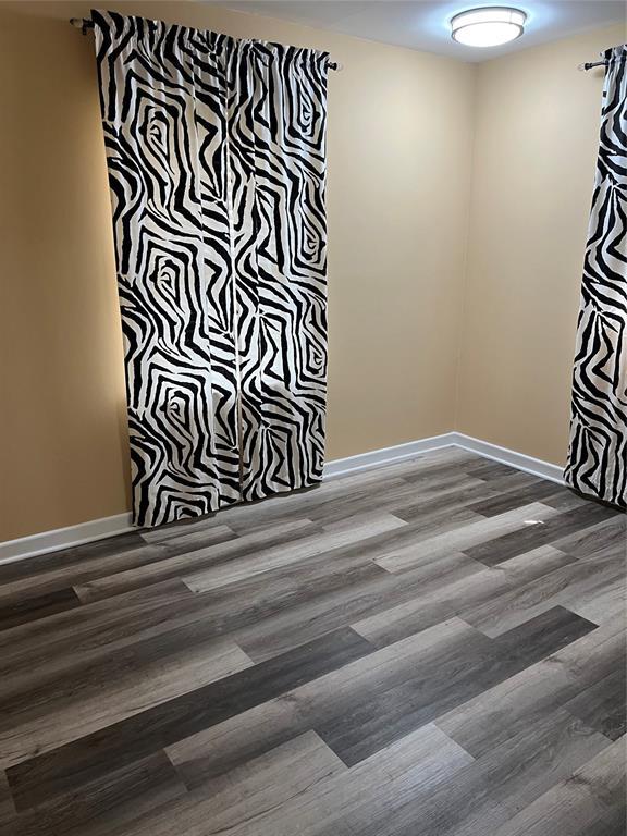 empty room with baseboards and wood finished floors