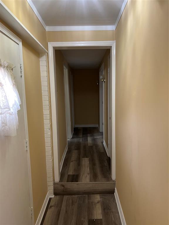 hall featuring baseboards, ornamental molding, and wood finished floors