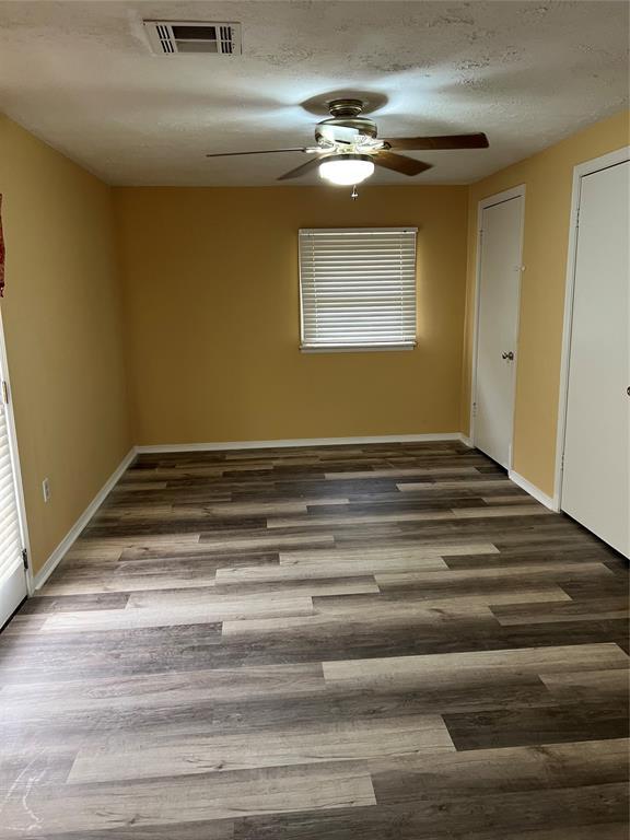 spare room with visible vents, baseboards, ceiling fan, and wood finished floors