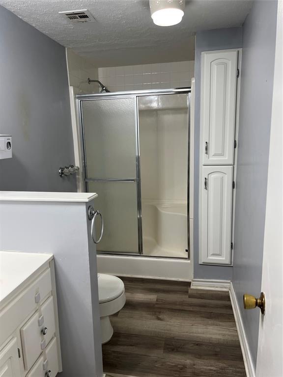 bathroom featuring visible vents, vanity, wood finished floors, and a shower stall