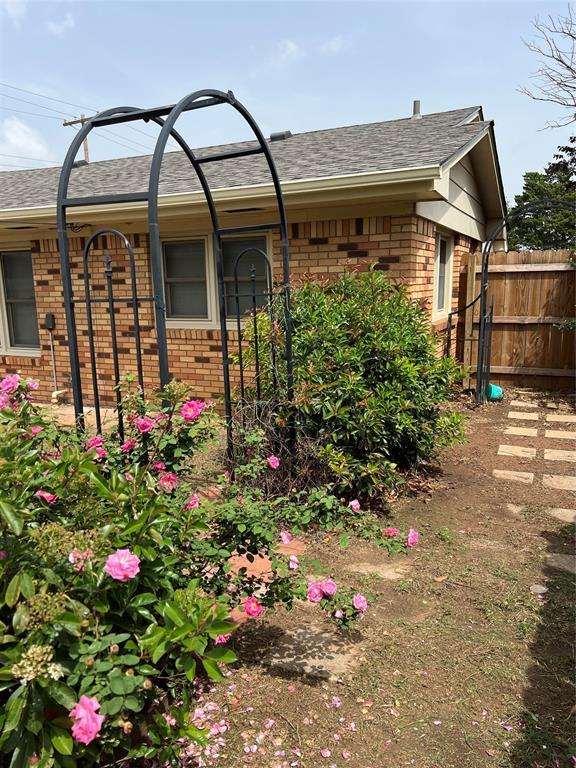exterior space featuring roof with shingles, fence, and brick siding