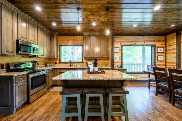 kitchen with a kitchen island, appliances with stainless steel finishes, light stone countertops, a sink, and wooden ceiling