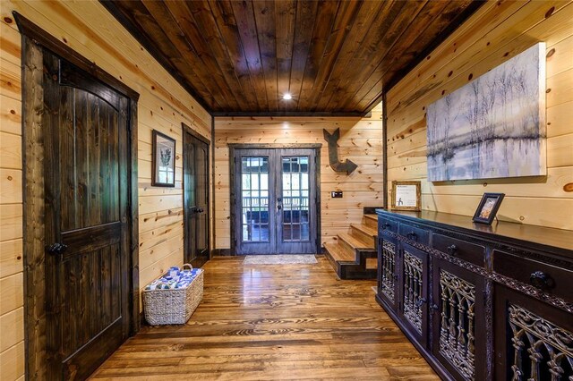 foyer with wooden walls, wooden ceiling, french doors, and wood finished floors