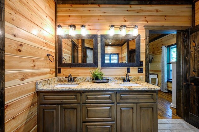 bathroom featuring a sink, wood walls, and double vanity