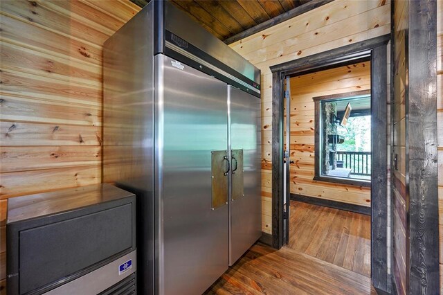 kitchen featuring high end refrigerator, wood walls, wood ceiling, and hardwood / wood-style flooring