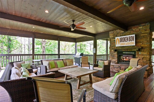 sunroom featuring beam ceiling, a ceiling fan, and an outdoor living space with a fireplace
