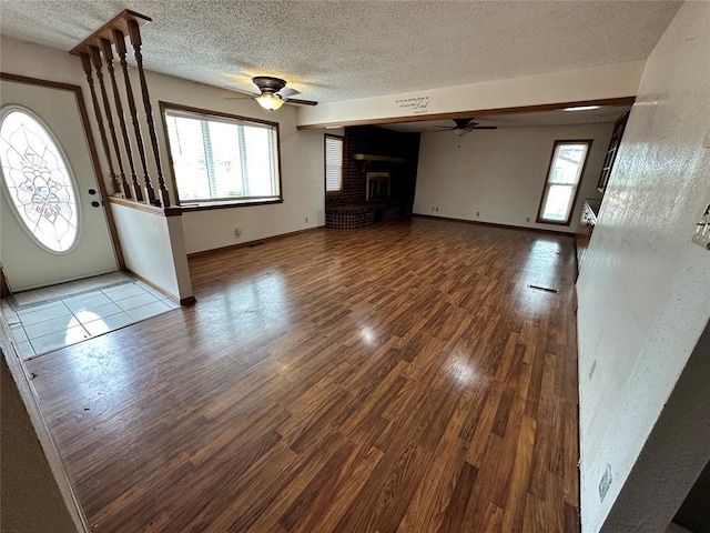 unfurnished living room with ceiling fan, plenty of natural light, and wood finished floors