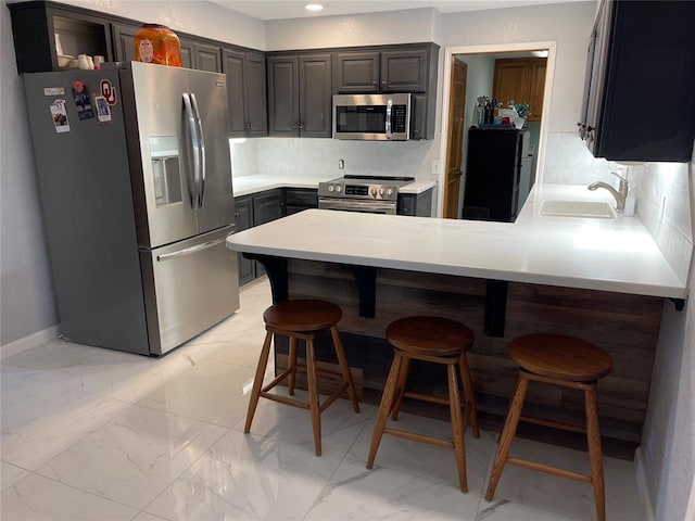 kitchen with a sink, decorative backsplash, stainless steel appliances, and a peninsula