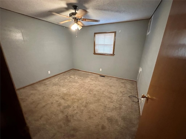carpeted empty room featuring baseboards, ceiling fan, a textured ceiling, and visible vents