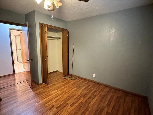 unfurnished bedroom featuring a textured ceiling, a closet, and wood finished floors