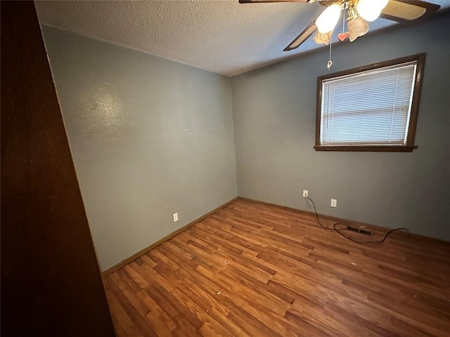 unfurnished room featuring baseboards, a ceiling fan, a textured ceiling, and wood finished floors