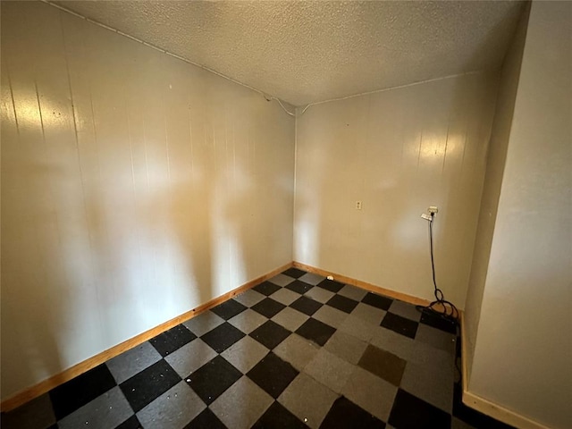 unfurnished room featuring dark floors, baseboards, and a textured ceiling