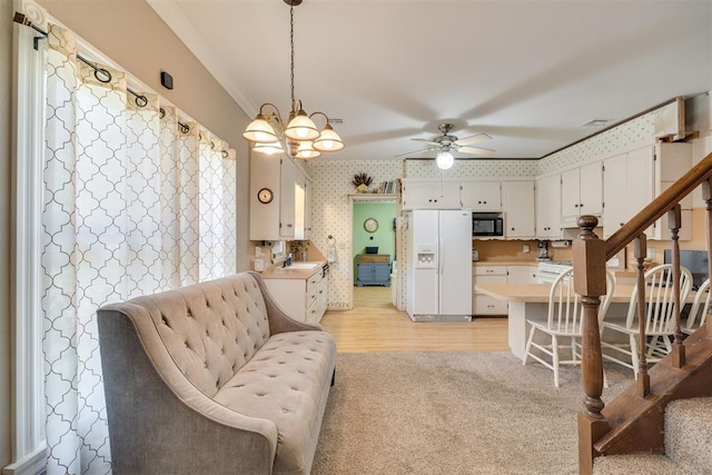 living area with stairs, wallpapered walls, light wood-type flooring, light colored carpet, and ceiling fan with notable chandelier