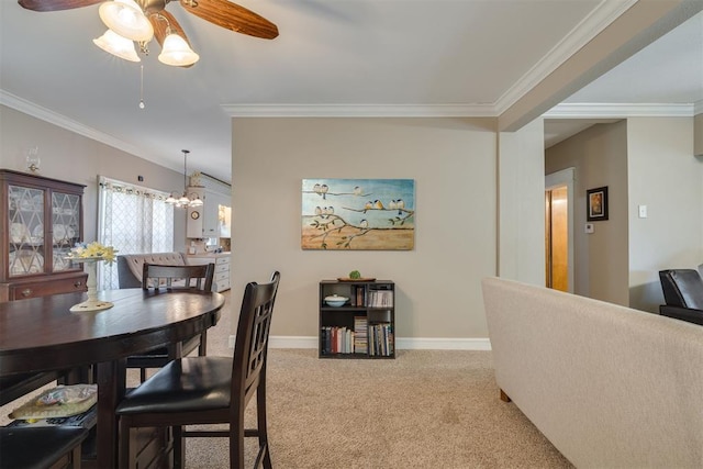 carpeted dining space with crown molding, baseboards, and ceiling fan with notable chandelier
