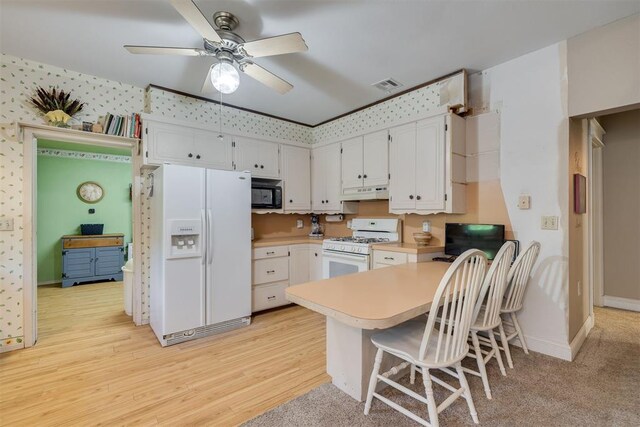 kitchen with white appliances, light countertops, a peninsula, a ceiling fan, and under cabinet range hood