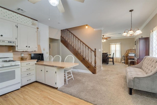 kitchen featuring visible vents, gas range gas stove, ceiling fan, under cabinet range hood, and white cabinets