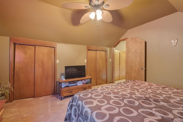 bedroom featuring a ceiling fan, carpet floors, lofted ceiling, multiple closets, and a textured wall