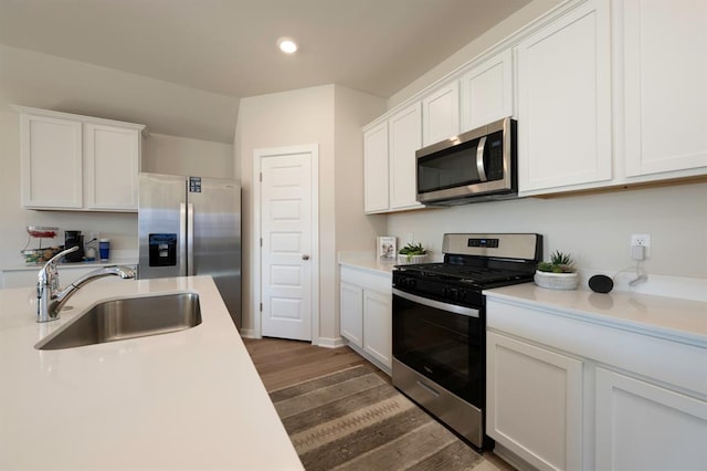 kitchen featuring a sink, appliances with stainless steel finishes, wood finished floors, and white cabinets