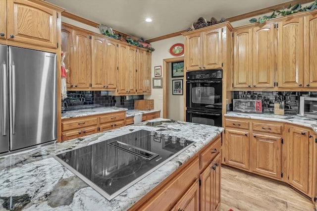 1008 Bavarian Dr, Edmond, OK 73034 - kitchen featuring black appliances, tasteful backsplash, light stone countertops, light wood-style floors, and recessed lighting