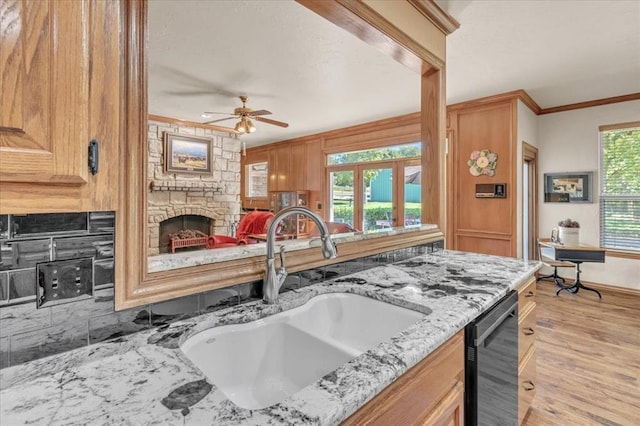 1008 Bavarian Dr, Edmond, OK 73034 - kitchen with a stone fireplace, ceiling fan, crown molding, light wood-style flooring, and light stone countertops