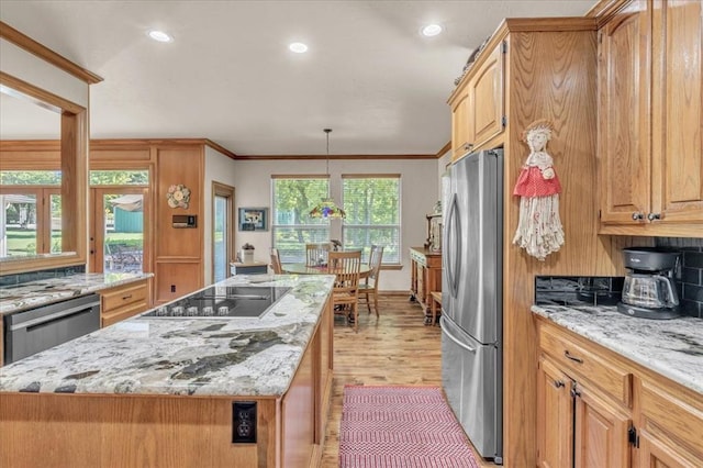 1008 Bavarian Dr, Edmond, OK 73034 - kitchen featuring appliances with stainless steel finishes, light wood-style flooring, a kitchen island, light stone counters, and ornamental molding